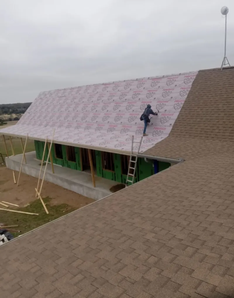 Worker preparing underlayment for a metal roof installation in Hazel Park